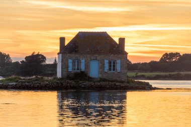 Gün batımında nehir kenarındaki ev