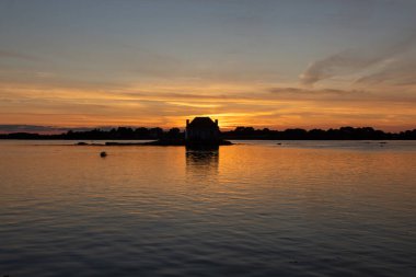 Gün batımında nehir kenarındaki ev