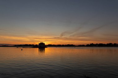 Gün batımında nehir kenarındaki ev