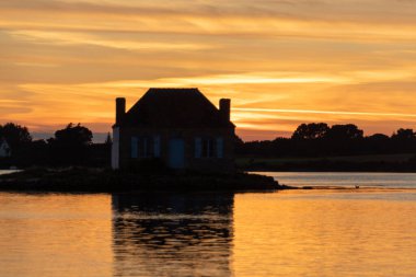 Gün batımında nehir kenarındaki ev