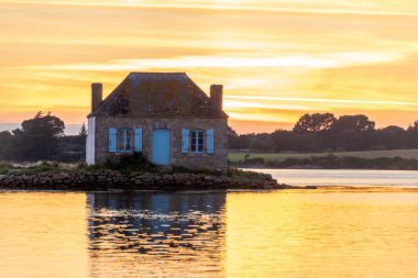 Gün batımında nehir kenarındaki ev