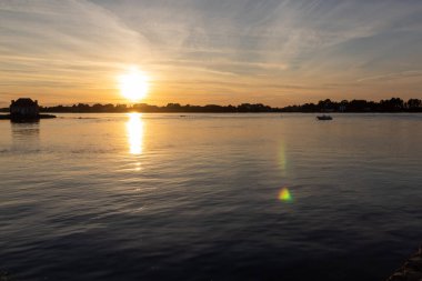 Gün batımında nehir kenarındaki ev