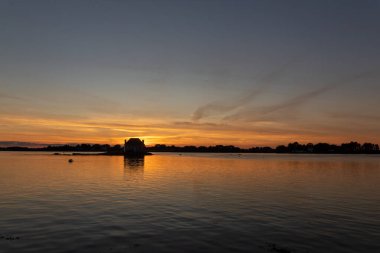 Gün batımında nehir kenarındaki ev