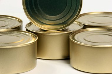 Beyaz ve gri arka planda birçok kapalı teneke kutu var. Balık ve et ürünleri için metal kutular
