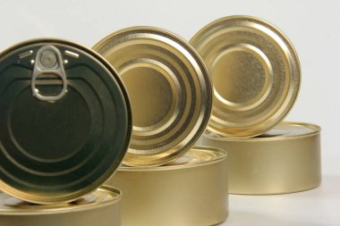 Beyaz ve gri arka planda birçok kapalı teneke kutu var. Balık ve et ürünleri için metal kutular