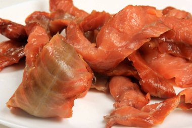 Beyaz arka planda soğuk füme somon şeritleri, tütsülenmiş balık ürünleri.