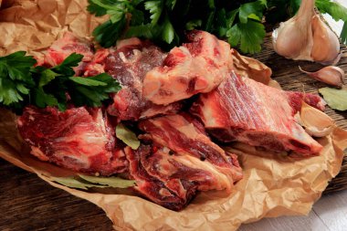 Çorba için sığır kemiği seçimi. Baharatlı taze et parçaları, maydanoz ve defne yaprakları beyaz arka planda.