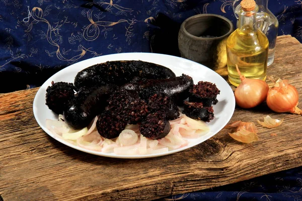 stock image Baked black pudding with pickled onions on a white plate. Sliced and fried blood sausage on a plate