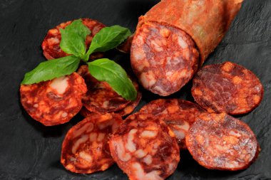 İspanyol domuz sucuğu salam dilimi siyah taş tabakta. Chorizo İberian ekstra sosis dilimi