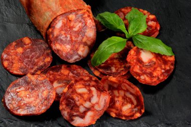 İspanyol domuz sucuğu salam dilimi siyah taş tabakta. Chorizo İberian ekstra sosis dilimi