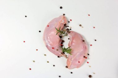 Kemikli çiğ tavşan bacağı ve beyaz arka planda biber.