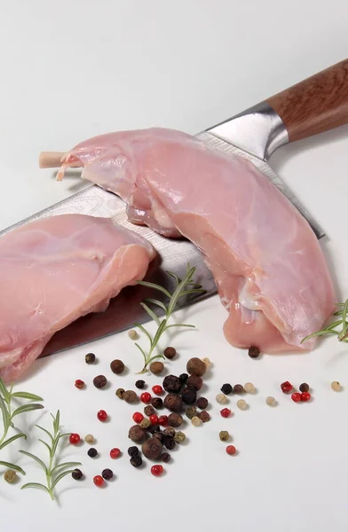 raw rabbit legs with bone with peppercorns on a white background