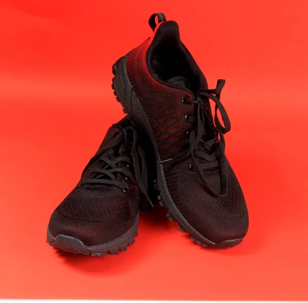 黑色和红色运动鞋主题为红色背景 一双网球鞋 — 图库照片