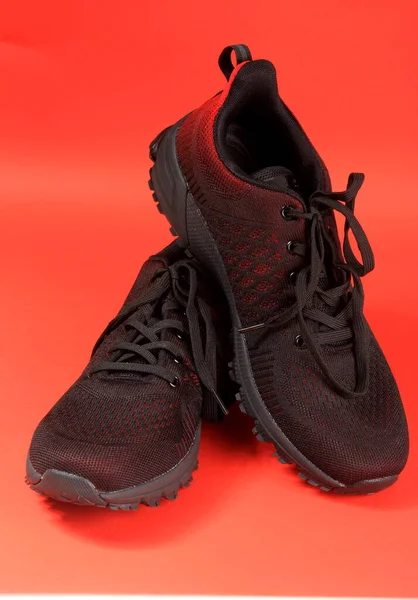 黑色和红色运动鞋主题为红色背景 一双网球鞋 — 图库照片