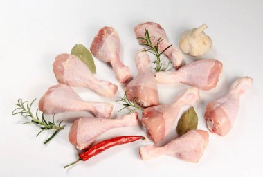 Beyaz arka planda baharatlı çiğ tavuk bacağı, yakın plan. Tavuk budu.