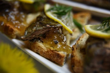 Beyaz bir tabakta, limonla süslenmiş bir sandviçin üzerinde kızarmış balık.