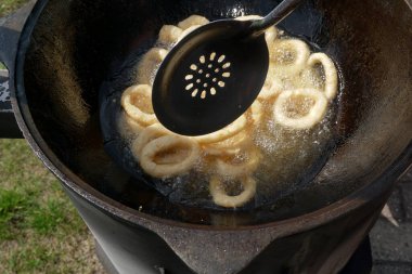       Tavada kızaran kalamar halkaları. Kızarmış soğan halkalarını kızgın yağda kızartma makinesinde yakın..                         