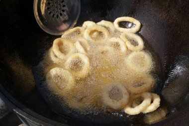   Tavada kızaran kalamar halkaları. Kızarmış soğan halkalarını kızgın yağda kızartma makinesinde yakın..                             