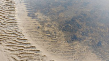 Güzel bir kumsalın kum sanatı. Kumda dalgalanan dalgalar