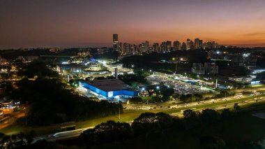 Curitiba Parana, Brezilya 'da. Hava görüntüsü. Binalar ve Tangu Parkı manzaralı harika bir gün batımı. Yansımalı göl