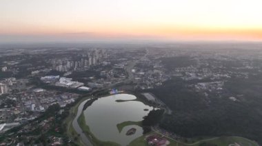 Curitiba Parana, Brezilya 'da. Hava görüntüsü. Binalar ve Tangua Park manzaralı harika bir gün batımı. Yansımalı göl.