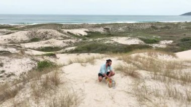 Sahilde piknik yaparken meyve yiyip su içen bir adam. Sağlık, sağlıklı beslenme ve açık hava aktivitesi kavramı.