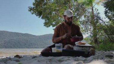Adam piknik sırasında sosisli hazırlayıp yiyor ve gölde yürüyor..
