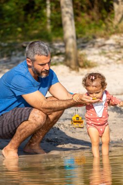 Genç beyaz bir aile güneşli bir öğleden sonra gölde piknik yapıyor..