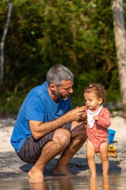 Genç beyaz bir aile güneşli bir öğleden sonra gölde piknik yapıyor..