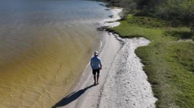 Adam yürüyor ve dışarıda koşuyor, göl kenarına park ediyor, hava manzarası var. Sağlık ve spor konsepti.