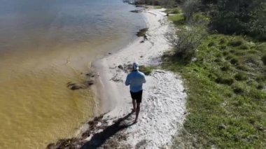 Adam yürüyor ve dışarıda koşuyor, göl kenarına park ediyor, hava manzarası var. Sağlık ve spor konsepti.