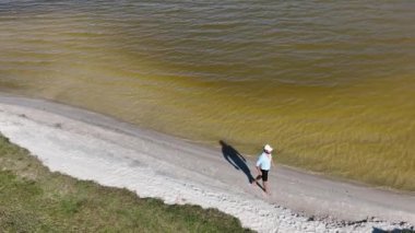 Adam yürüyor ve dışarıda koşuyor, göl kenarına park ediyor, hava manzarası var. Sağlık ve spor konsepti.