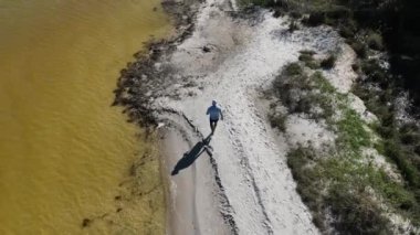 Adam yürüyor ve dışarıda koşuyor, göl kenarına park ediyor, hava manzarası var. Sağlık ve spor konsepti.