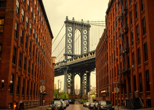 A stunning stock photo of the iconic Manhattan Bridge, framed by the vibrant DUMBO neighborhood in Brooklyn. The photo captures the bridge's neo-Gothic towers and its breathtaking views of the East River and the Manhattan skyline. Perfect for use in
