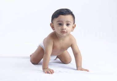 Beyaz arka planda bebek bezli sevimli bir oğlan, meraklı ve oyuncu görünüyor. Ebeveynlik, çocuk bakımı, bebek büyümesi, gelişme ve aile sevgisi konuları için mükemmel.