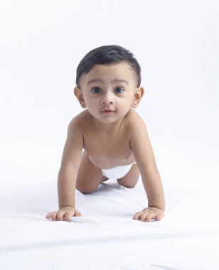 Beyaz arka planda bebek bezli sevimli bir oğlan, meraklı ve oyuncu görünüyor. Ebeveynlik, çocuk bakımı, bebek büyümesi, gelişme ve aile sevgisi konuları için mükemmel.