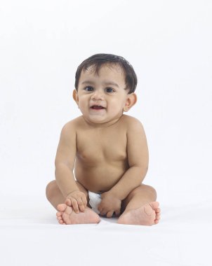 Parlak stüdyo ortamında şirin bebek portresi, doğal masumiyetle dik oturmak, ebeveynlik, çocuk bakımı, sağlık ve yaşam tarzı kavramları için ideal..