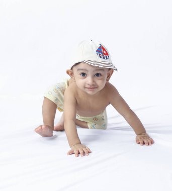 Başında şapka olan şirin bir bebek bezi, stüdyoda çekilen eğlenceli pozlar, çocukluk gelişimini, aktivitelerini ve keşiflerini simgeliyor..