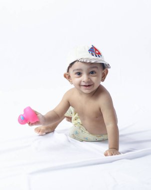 Sürünen çocuğun oyuncak ile bebek portresi, stüdyo ortamında bebek bezi giymek, öğrenim, büyüme, keşif ve çocuk bakımı kavramları için ideal.