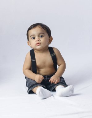 Pantolon askısı içinde bebek portresi, beyaz arka planda oturan şık çocuk moda, çocukluk, ebeveynlik ve yaşam tarzı tasvirleri için mükemmel görünüyor..