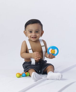 Oyuncak oyuncaklı şirin bebek portresi, stüdyo arka planında siyah pantolon askısı, ebeveynlik, aile ve çocukluk kavramları için ideal..