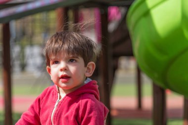 Güneşli bir günde dışarıda oyun parkında eğlenen sevimli küçük bir çocuk. Çocukluk kavramı.