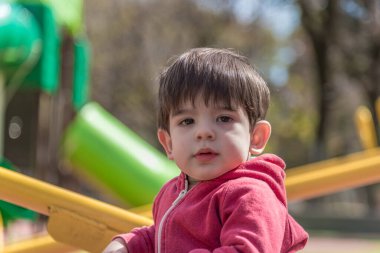 Parktaki oyun parkında eğlenirken kameraya bakan küçük bir çocuğun portresi. Çocukluk kavramı.