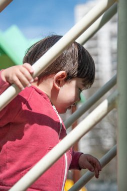 Parkta dışarıda oynarken merdivenlerden çıkan küçük bir çocuğun yakın görüntüsü. Çocukluk kavramı.