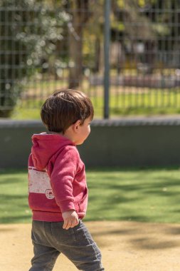 Küçük çocuk parktaki oyun parkında yürüyor. Çocukluk kavramı.