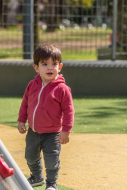 Parktaki oyun parkında duran küçük çocuk. Çocukluk kavramı.