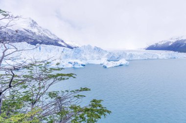 Uzakta Perito Moreno buzdağıyla güzel mavi bir göl Gökyüzü bulutlu ve su sakin