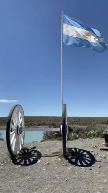 İki eski moda tekerleğin üzerinde bir Arjantin bayrağı dalgalanıyor. Bayrak mavi ve beyaz