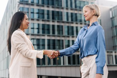 İki zarif iş kadını el sıkışıyor - Asyalı ve beyaz kadınlar arasında anlaşma anlaşması