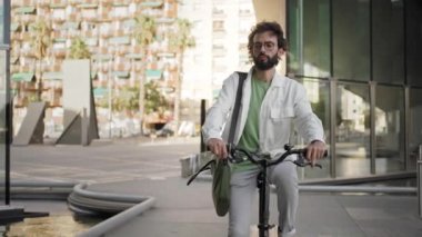 Bisikletle işe gelen genç profesyonel bir adam, bisikleti iş yerinin yakınına park ediyor - şehirde sağlıklı yaşam tarzı